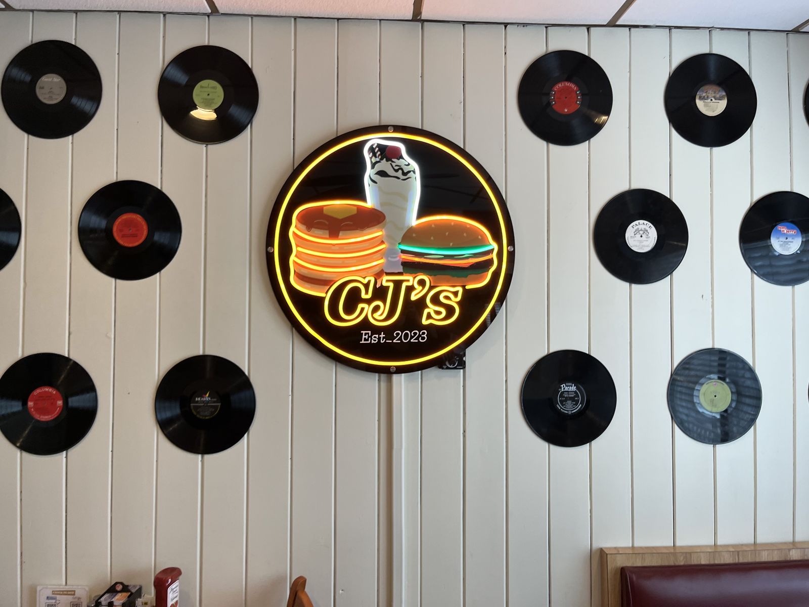 CJ's neon logo sign on the record wall